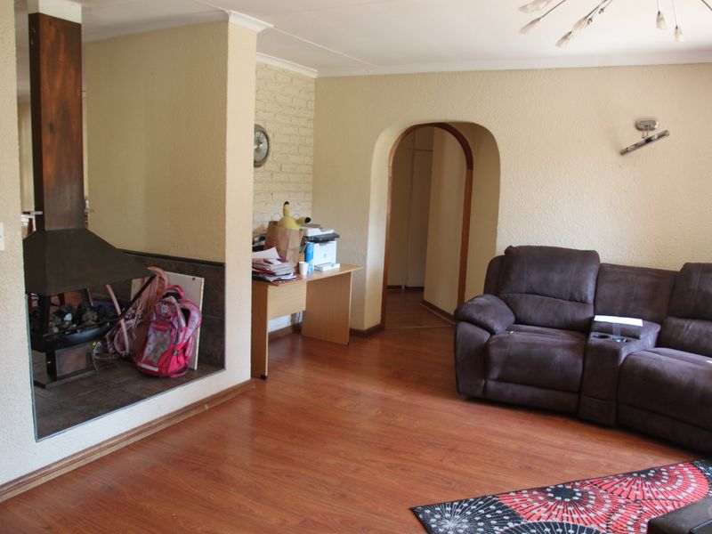 A living room featuring laminate flooring, an arched doorway, and a freestanding fireplace set against an exposed brick feature wall.