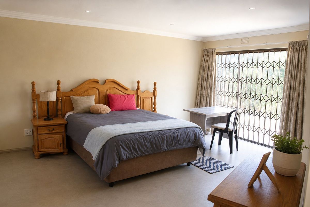 A spacious bedroom featuring neutral walls, recessed downlighting, and a sliding security gate leading to the exterior.