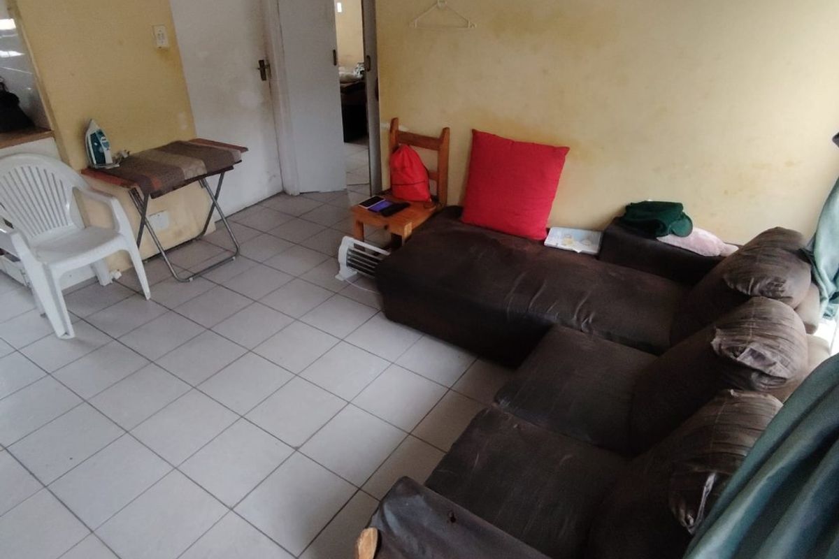 A living room area featuring ceramic floor tiles and multiple internal doors, currently requiring wall repairs and repainting to improve the overall condition.