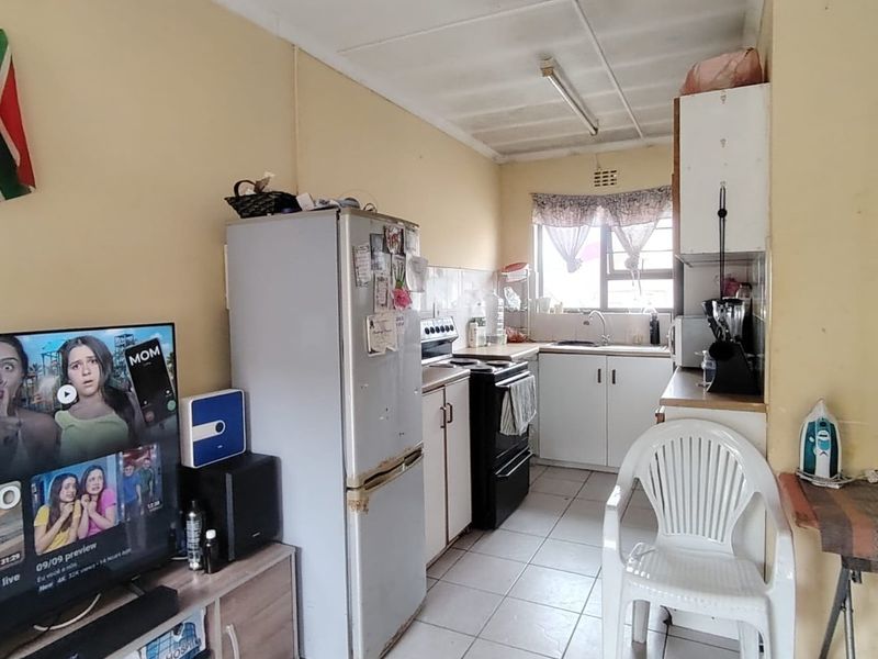 Compact kitchen featuring tiled flooring, built-in cabinetry, and a functional layout. The space would benefit from cosmetic updates to modernize the finishes.