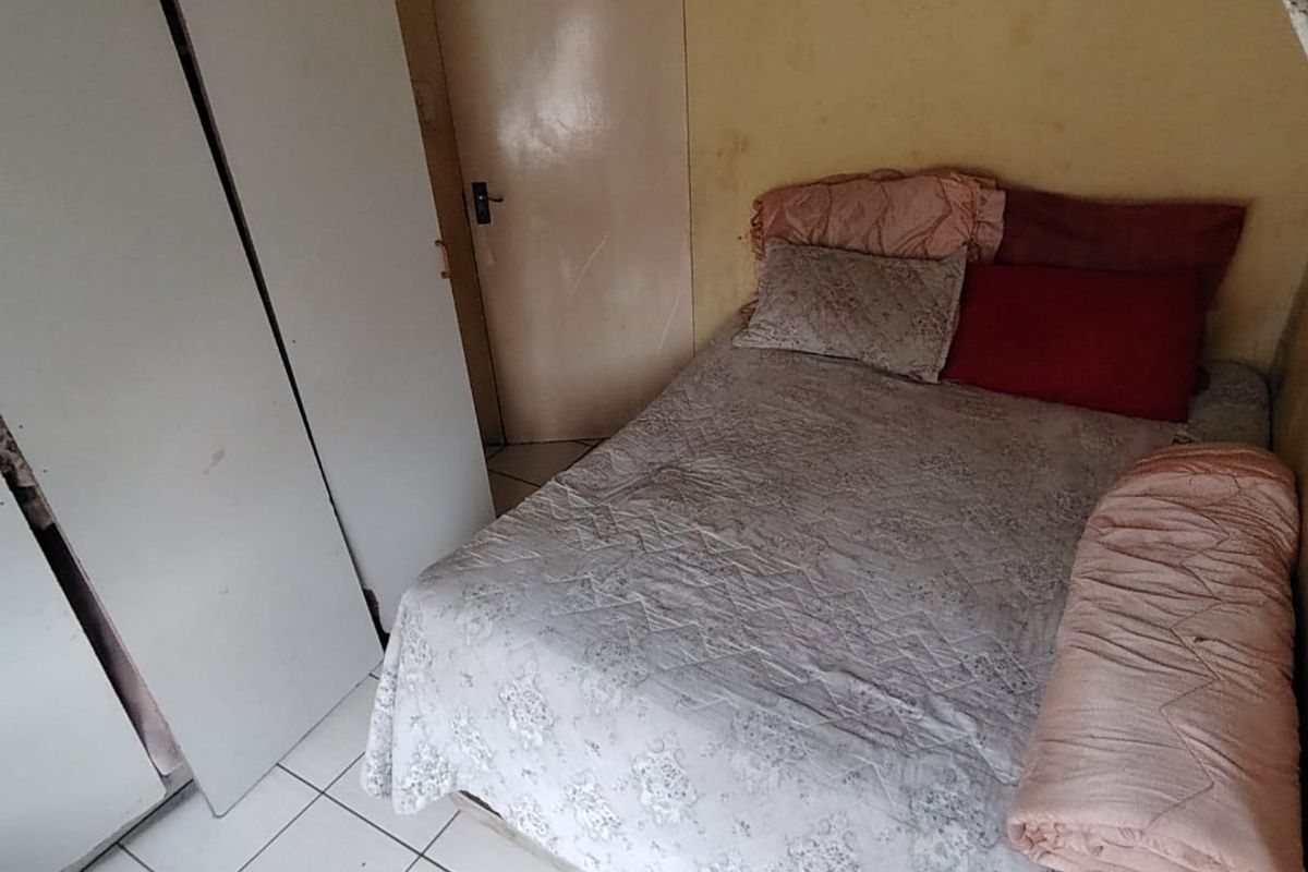A bedroom featuring tiled flooring and a built-in wardrobe, currently requiring cosmetic updates to the wall finishes.