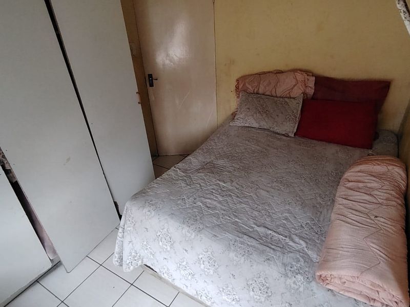 A bedroom featuring tiled flooring and a built-in wardrobe, currently requiring cosmetic updates to the wall finishes.