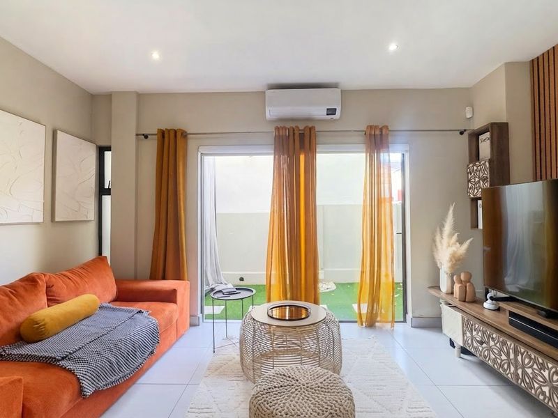 Modern living room featuring tiled flooring, recessed lighting, a split-system air conditioner, and sliding glass doors providing access to the outdoor area.