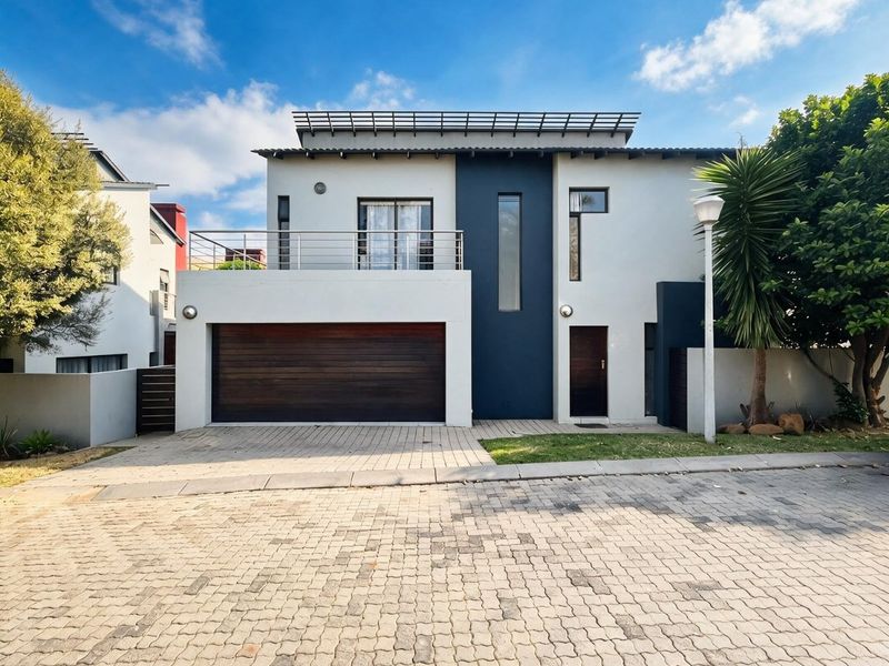 Modern double-story residential home featuring a sleek facade, integrated double garage, and an upper-level balcony with metal railings.