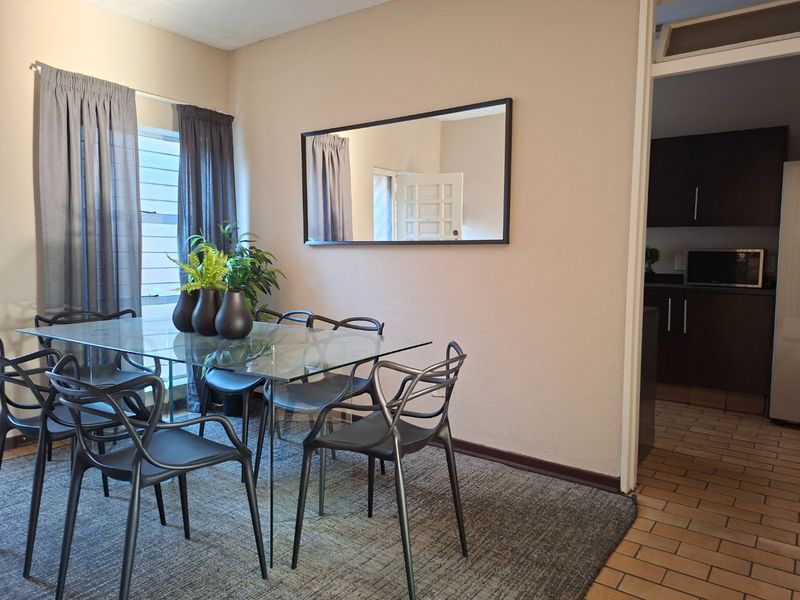 A dining area featuring tiled flooring and a view into the adjacent kitchen, providing a functional space for meals.