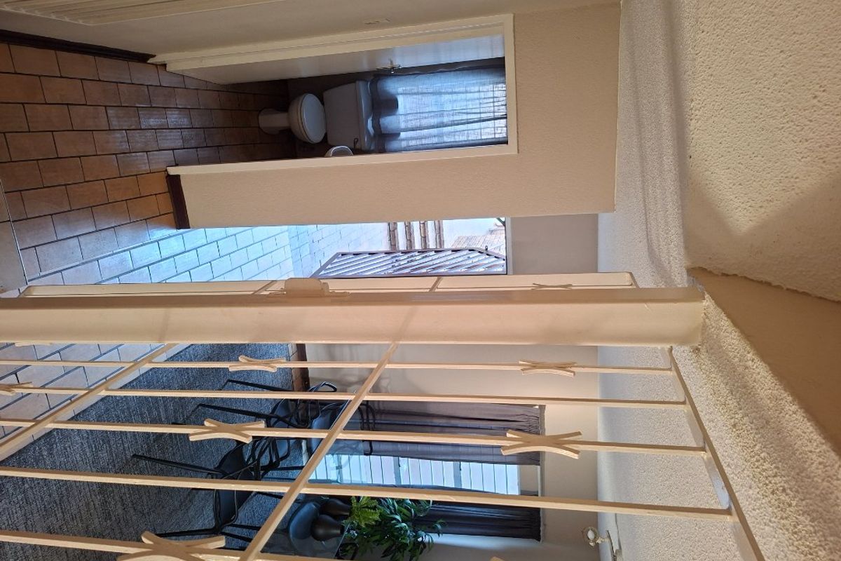 A living area featuring tiled flooring and a security gate, showing signs of age and wear throughout the space.