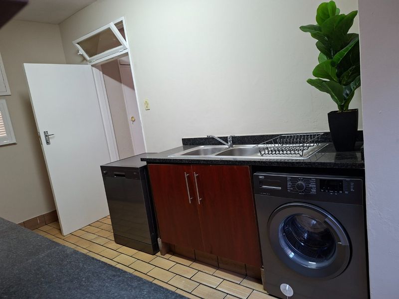 A functional laundry area featuring a double bowl sink, granite countertops, and dedicated plumbing connections for appliances.