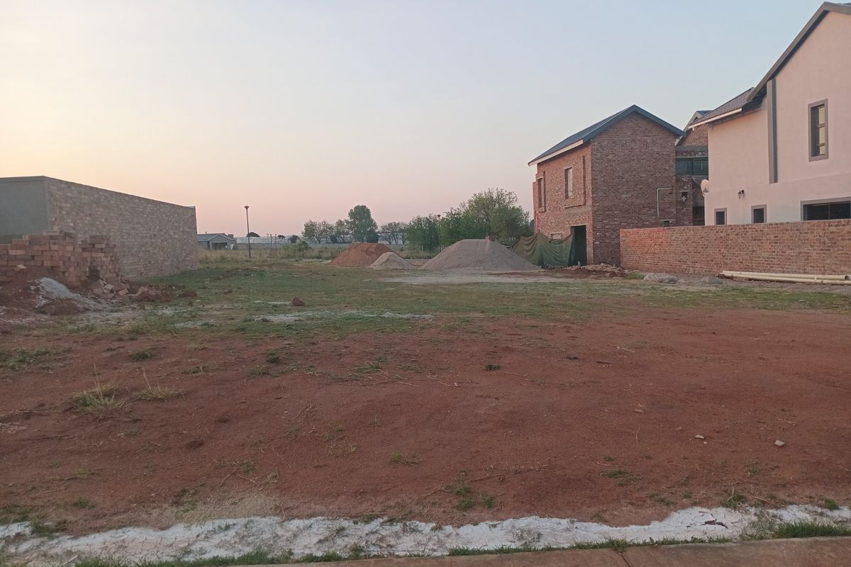 A vacant residential plot featuring boundary walls and some construction materials, offering a blank canvas for future development.