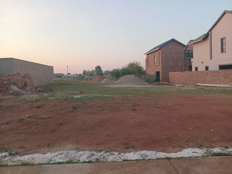 A vacant residential plot featuring boundary walls and some construction materials, offering a blank canvas for future development.