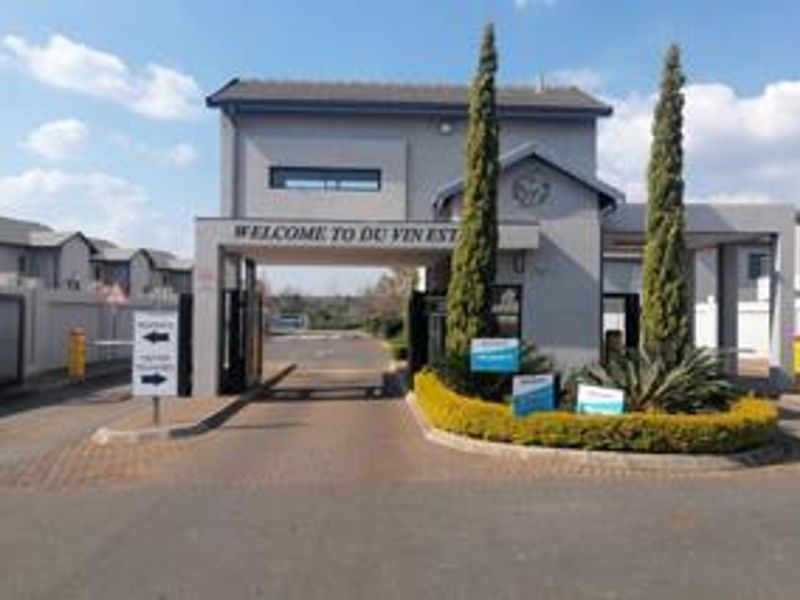 The entrance to Du Vin Estate featuring a modern security gatehouse, automated access control, and well-maintained landscaped garden beds.