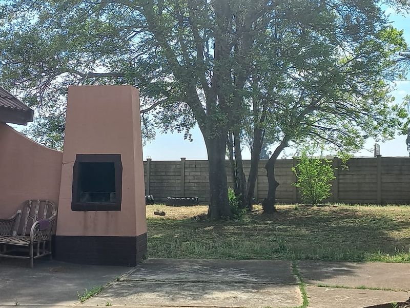Rear garden area featuring a concrete patio, built-in braai, and perimeter walling, offering a private outdoor space.