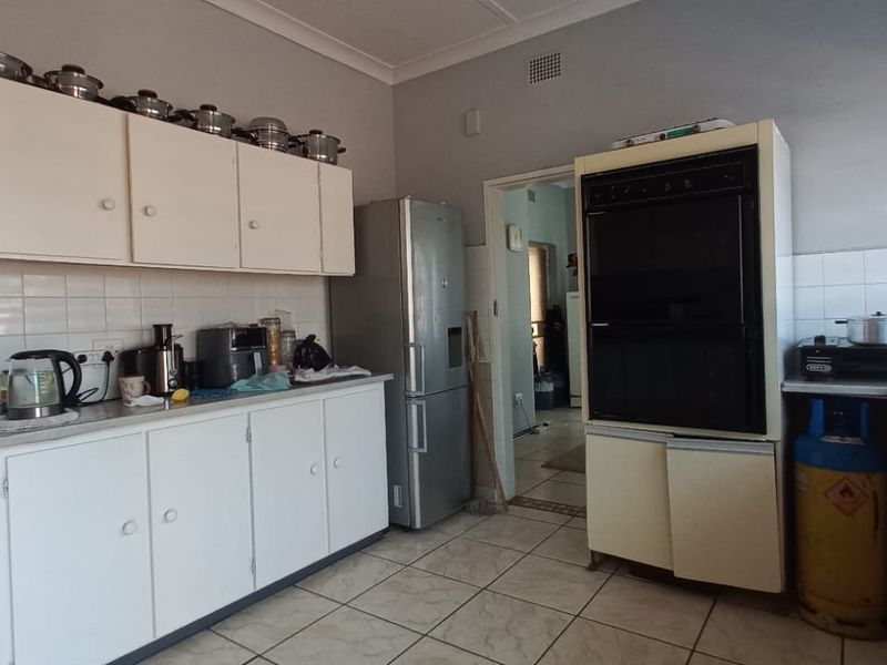 A functional kitchen featuring white built-in cabinetry, a double wall oven, tiled backsplash, and tiled flooring, offering a practical layout for daily use.