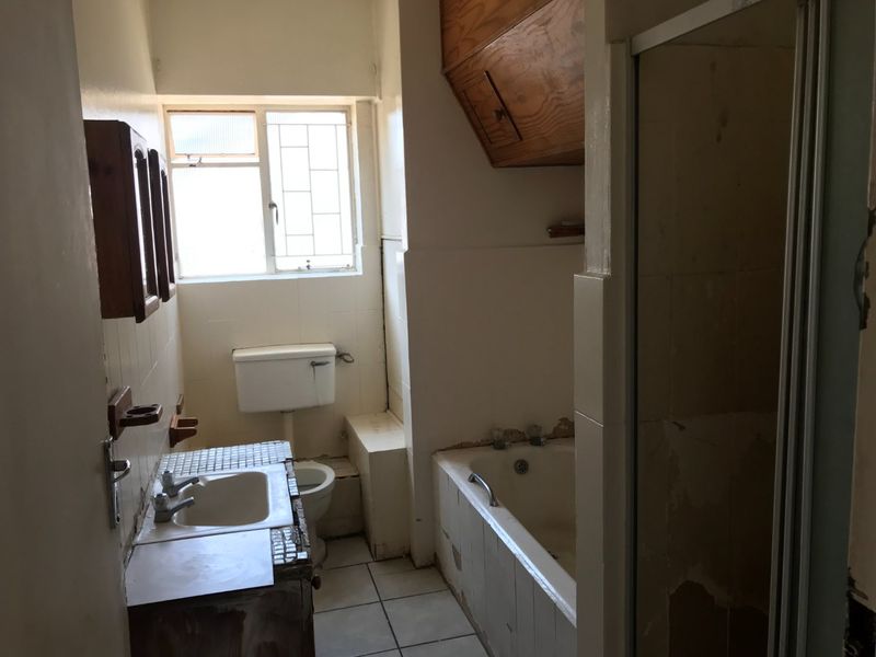 A dated bathroom featuring a built-in vanity, bathtub, shower enclosure, and toilet, requiring renovation to update the finishes and fixtures.