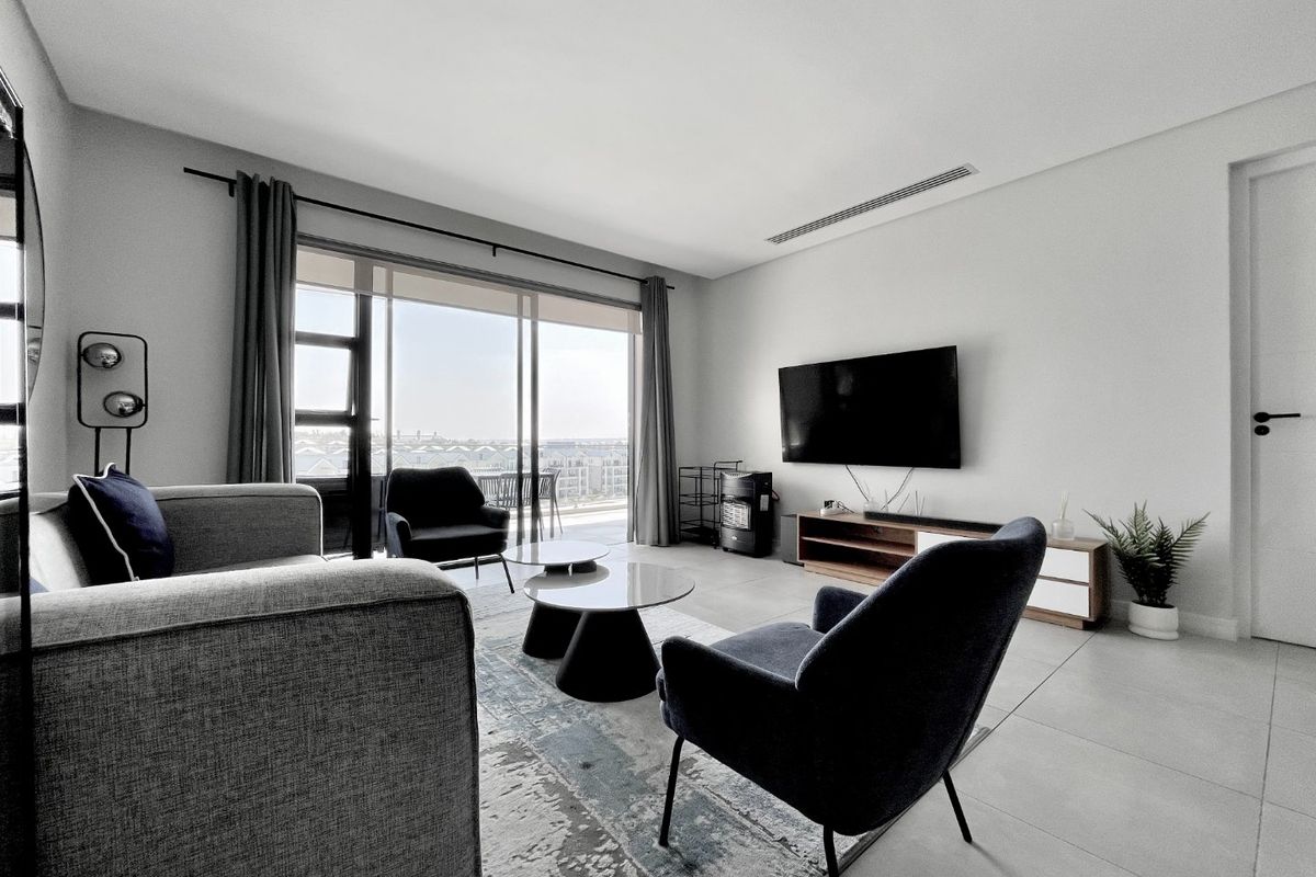 Modern living room featuring large sliding glass doors leading to a balcony, ducted air conditioning, and neutral tiled flooring.
