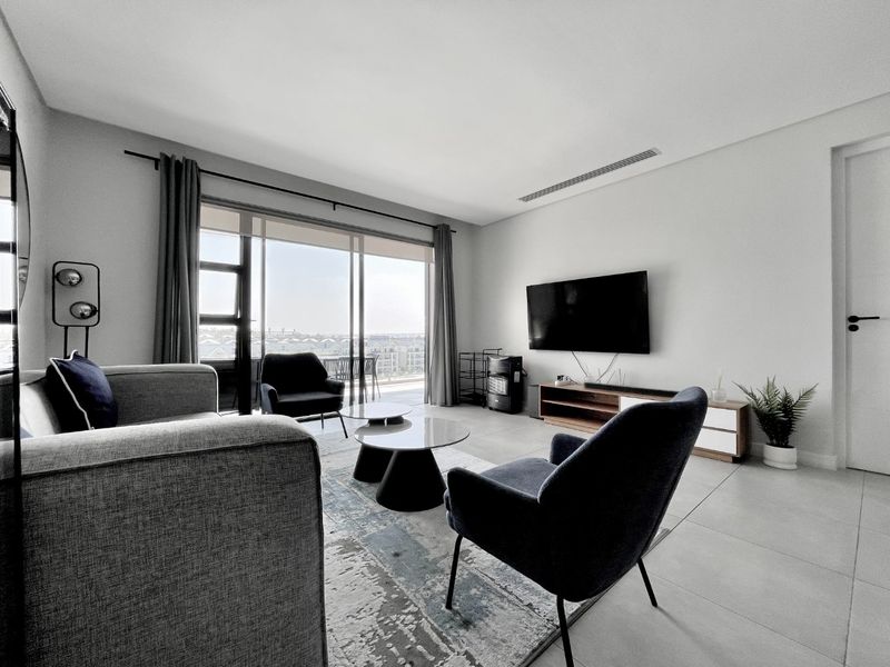 Modern living room featuring large sliding glass doors leading to a balcony, ducted air conditioning, and neutral tiled flooring.