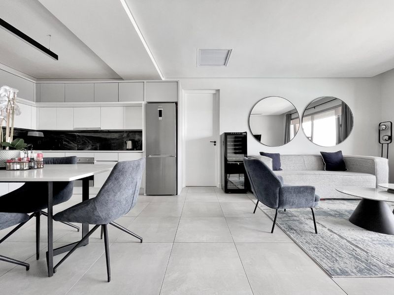 Modern open-plan living and kitchen area featuring sleek cabinetry, integrated appliances, large format floor tiles, and contemporary recessed lighting.