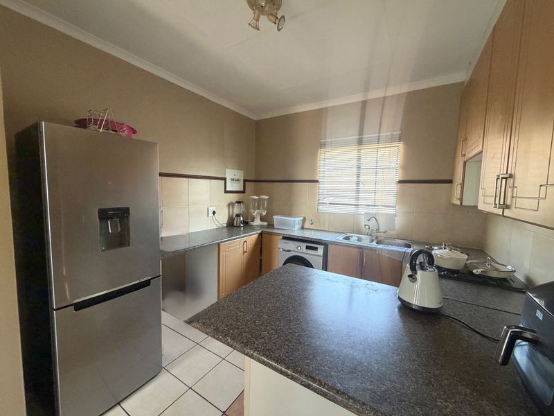 Functional kitchen featuring laminate cabinetry, granite countertops, double basin sink, and tiled flooring, offering a practical layout for daily meal preparation.
