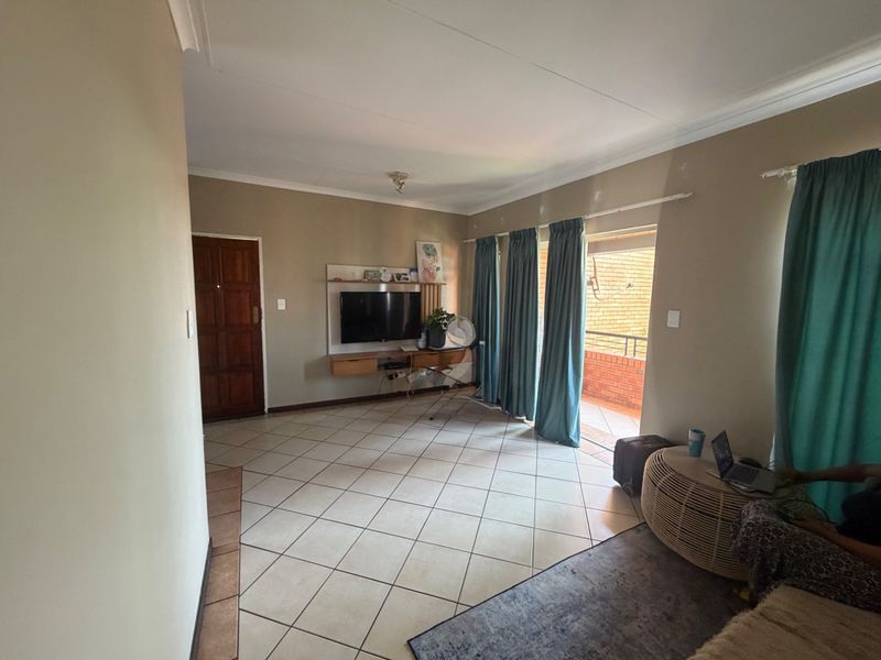 A living room featuring tiled flooring, a built-in wall unit, and direct access to an outdoor balcony through a sliding glass door.
