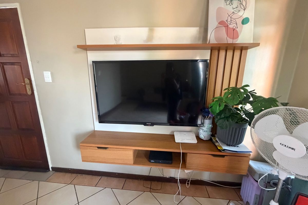 A living room area featuring a built-in wooden wall unit and tiled flooring.