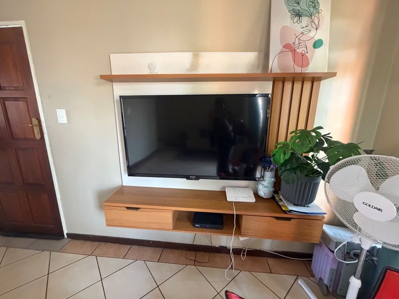 A living room area featuring a built-in wooden wall unit and tiled flooring.