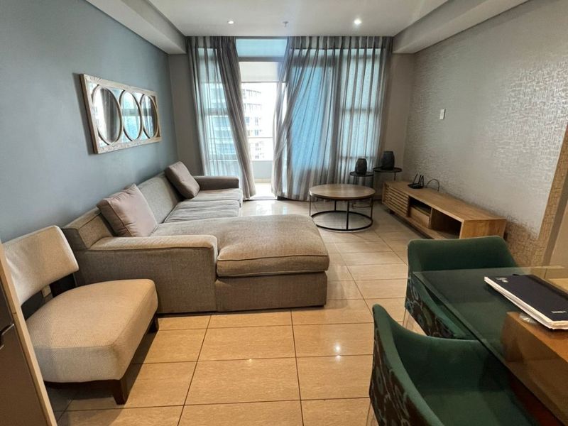 Open-plan living area featuring tiled flooring, recessed downlighting, and access to a private balcony through large sliding glass doors.