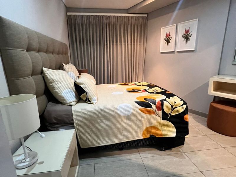 A well-maintained bedroom featuring neutral tiled flooring, recessed ceiling lighting, and floor-to-ceiling curtains.