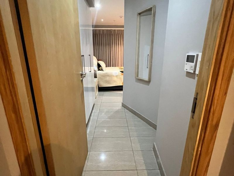 A well-maintained hallway featuring tiled flooring, built-in storage cupboards, and integrated climate control systems, leading into a bedroom area.