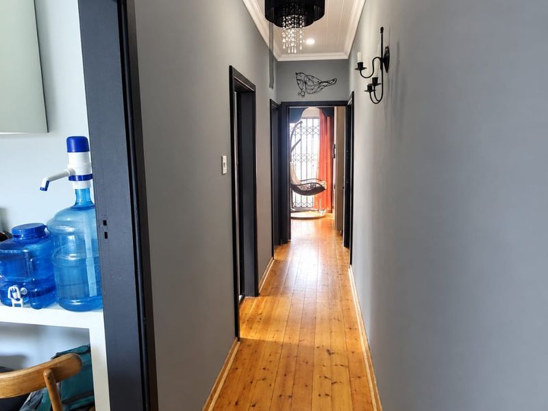 A well-maintained hallway featuring polished timber flooring, tongue and groove ceiling detailing, and elegant wall sconce lighting.
