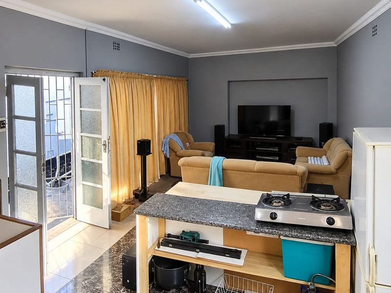 Open plan living area featuring a kitchen island with a gas hob, granite countertop, and direct access to an outdoor area through a security gate.