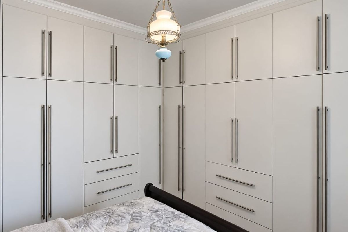 A well-appointed bedroom featuring extensive floor-to-ceiling built-in cabinetry with integrated drawers and modern brushed metal hardware.