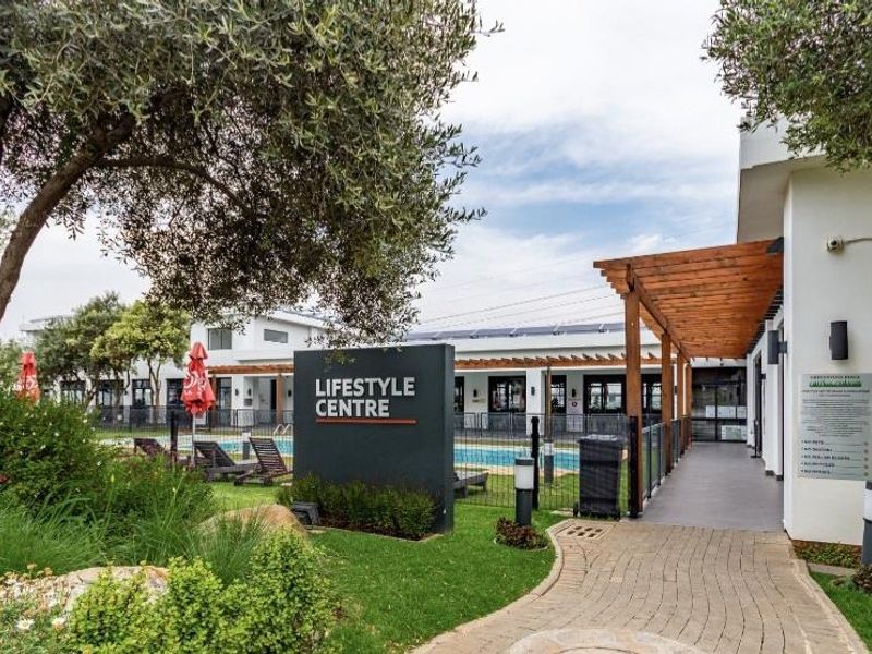 Exterior view of the apartment complex lifestyle centre featuring a swimming pool, landscaped gardens, and a covered walkway.