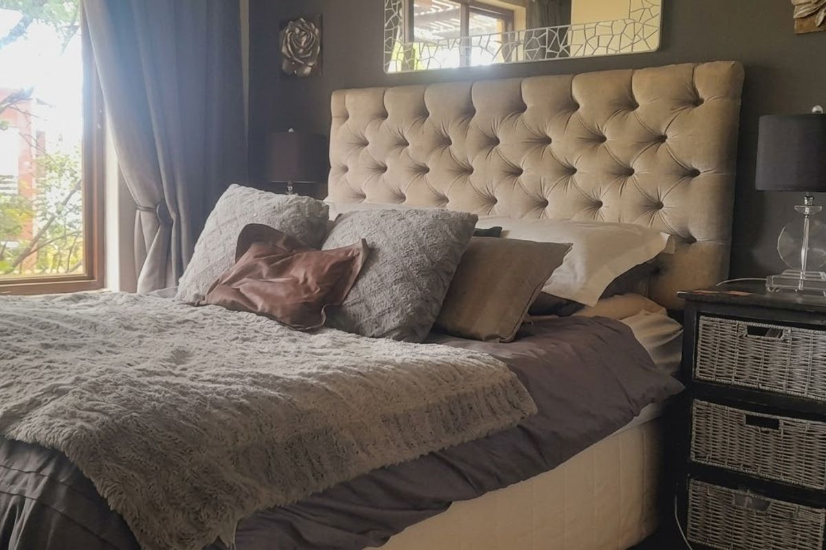 A cozy bedroom featuring a large window that allows for natural light and views of the surrounding greenery.