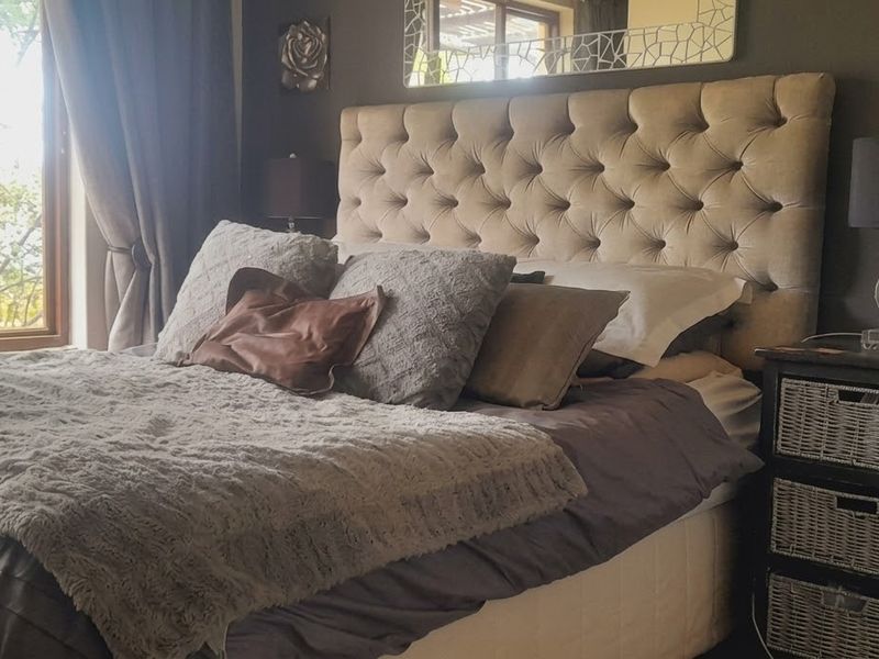 A cozy bedroom featuring a large window that allows for natural light and views of the surrounding greenery.