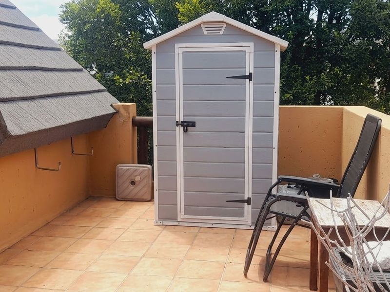 A private balcony area featuring tiled flooring, a protective parapet wall, and a pitched roof overhang, providing an outdoor space for relaxation.