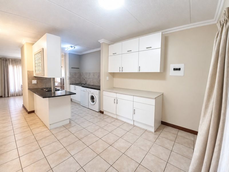 A functional kitchen featuring white cabinetry, stone countertops, tiled flooring, and integrated appliances, offering a clean and practical layout for daily use.