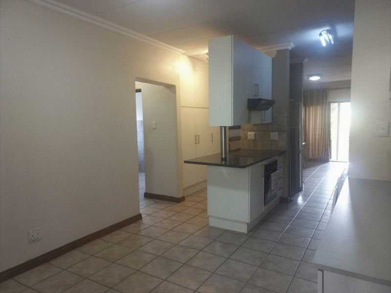 Open plan kitchen and living area featuring tiled flooring, built-in cabinetry, and a central kitchen island with integrated oven and extractor fan.