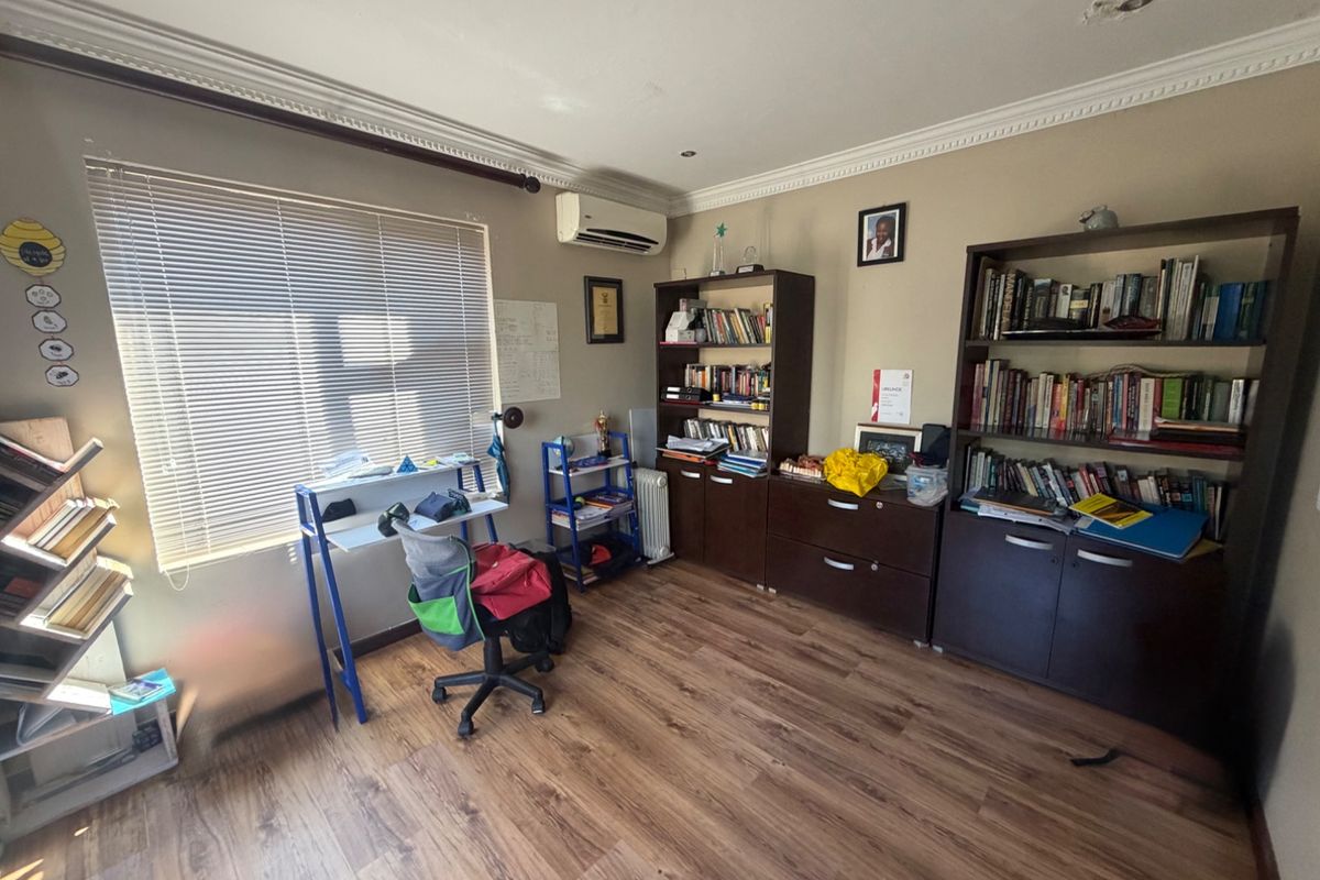 A bedroom featuring laminate flooring, an air conditioning unit, and venetian blinds, with some minor ceiling damage visible.