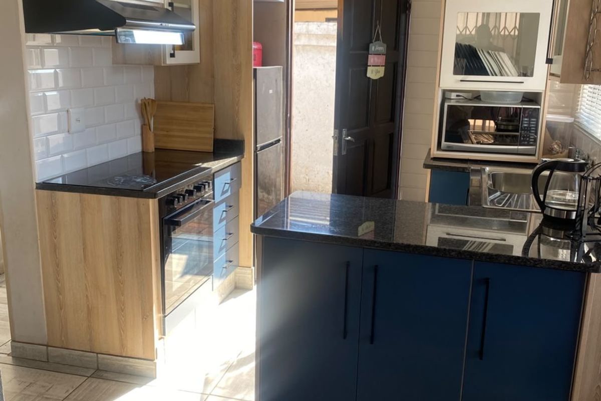 A functional kitchen featuring two-tone cabinetry, granite countertops, subway tile backsplash, and integrated appliances with direct access to the exterior.