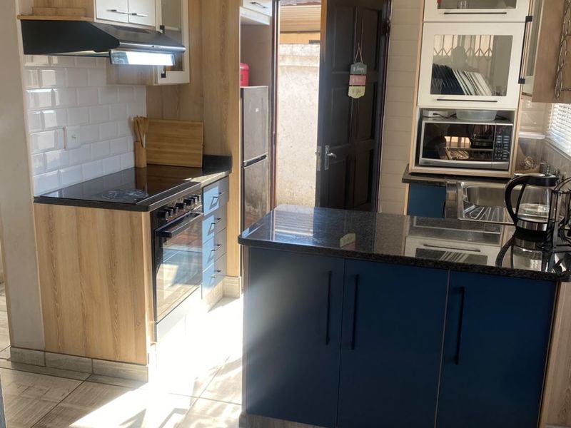 A functional kitchen featuring two-tone cabinetry, granite countertops, subway tile backsplash, and integrated appliances with direct access to the exterior.