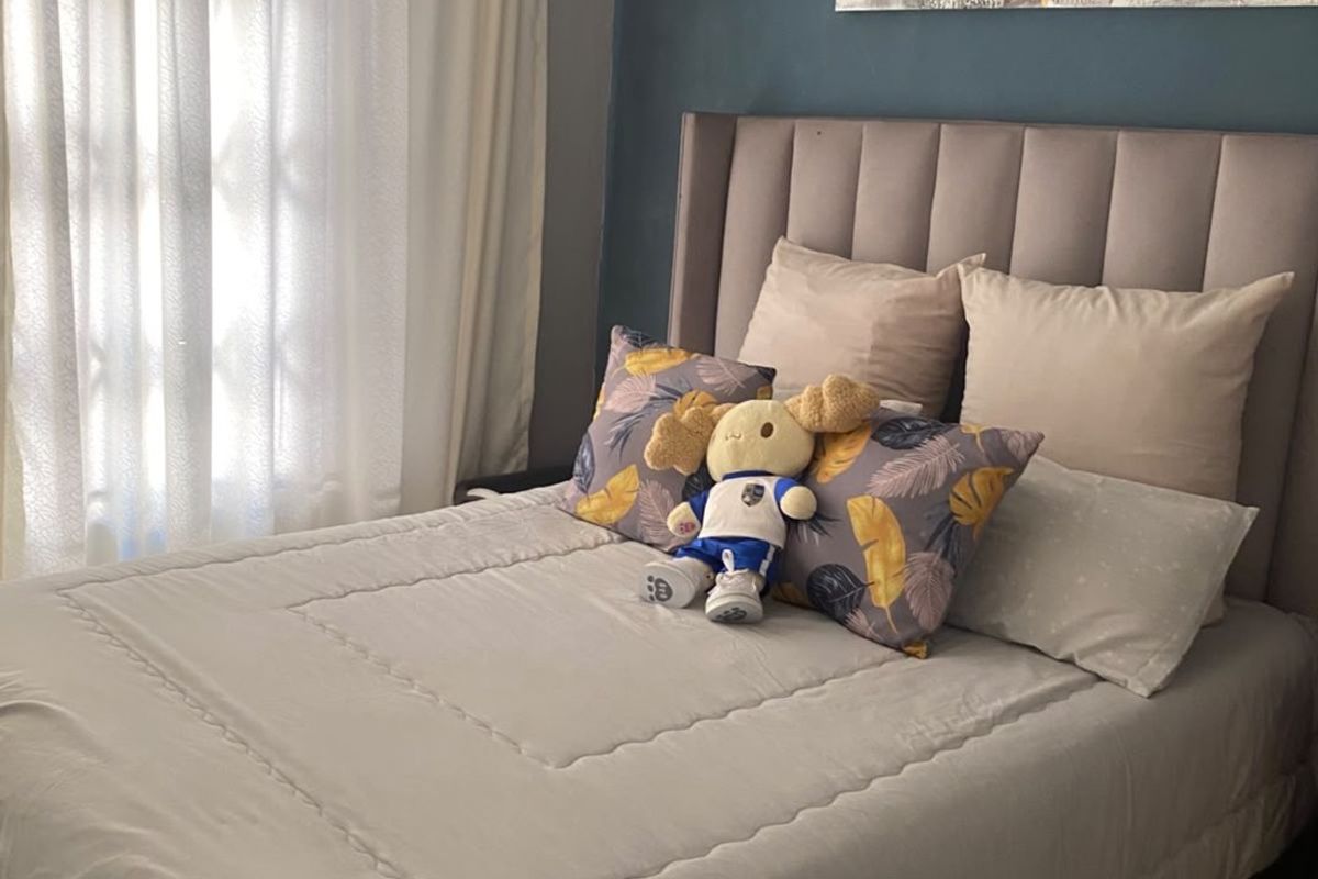 A cozy bedroom featuring a dark blue accent wall and neutral-toned window treatments, providing a comfortable and private sleeping space.