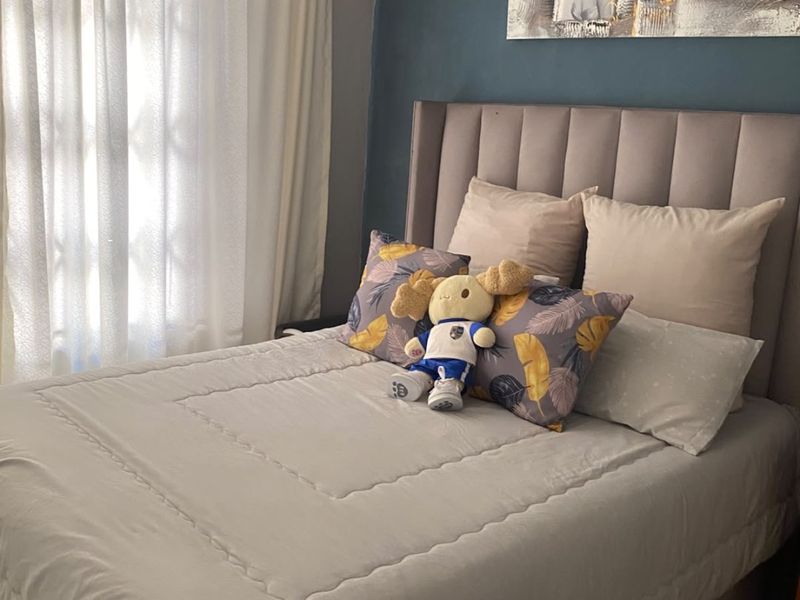 A cozy bedroom featuring a dark blue accent wall and neutral-toned window treatments, providing a comfortable and private sleeping space.