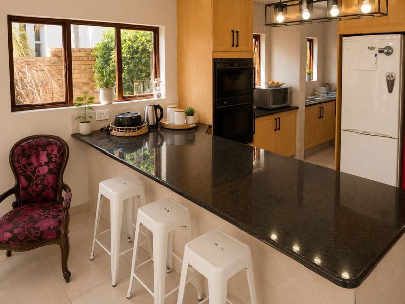A functional kitchen featuring granite countertops, wooden cabinetry, built-in oven, and a breakfast bar area with tiled flooring.