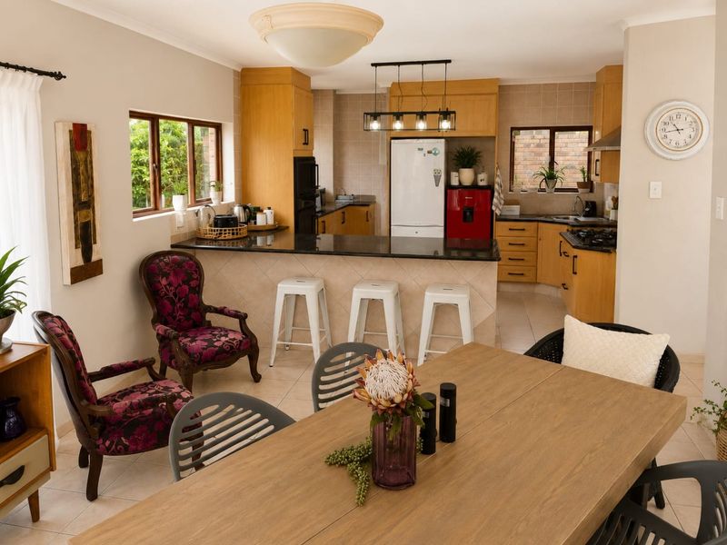 Open-plan kitchen and dining area featuring wooden cabinetry, granite countertops, a breakfast bar, and tiled flooring, creating a functional and connected living space.