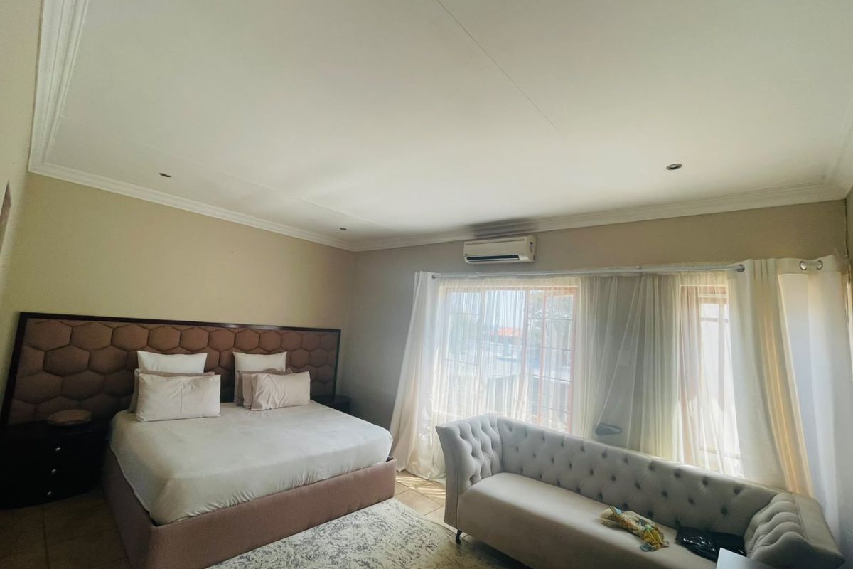 Spacious bedroom featuring a wall-mounted air conditioning unit, recessed ceiling lighting, and decorative crown molding.