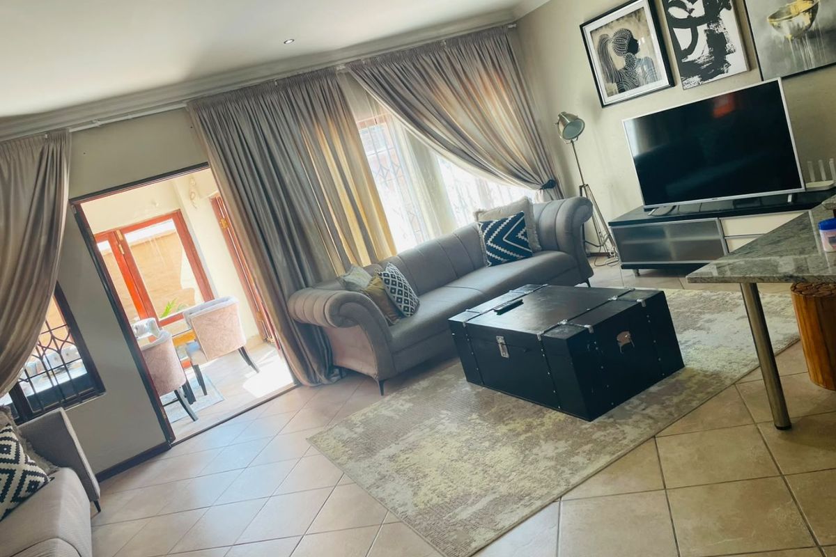 A comfortable living room featuring tiled flooring, recessed lighting, and an air conditioning unit, with direct access to an adjoining patio area.