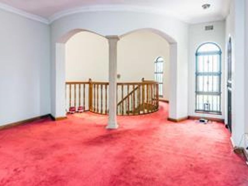 Spacious landing area featuring arched architectural details, a central column, and a wooden balustrade overlooking the staircase.