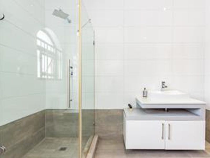 Modern bathroom featuring a glass-enclosed shower with a rain shower head and a sleek vanity cabinet with a vessel sink.