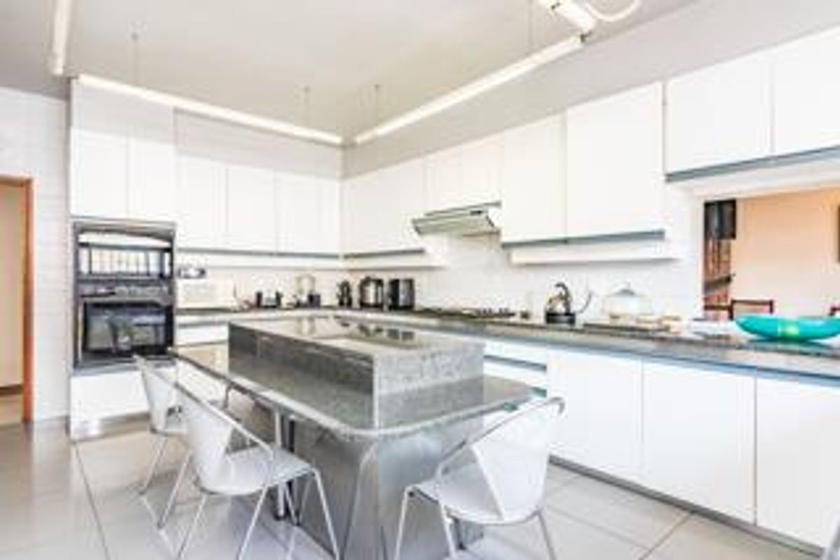 Modern kitchen featuring white cabinetry, granite countertops, a central island, and built-in oven, providing a functional and bright workspace.