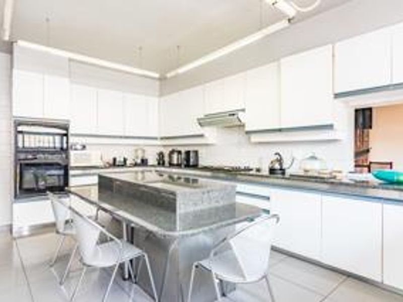 Modern kitchen featuring white cabinetry, granite countertops, a central island, and built-in oven, providing a functional and bright workspace.