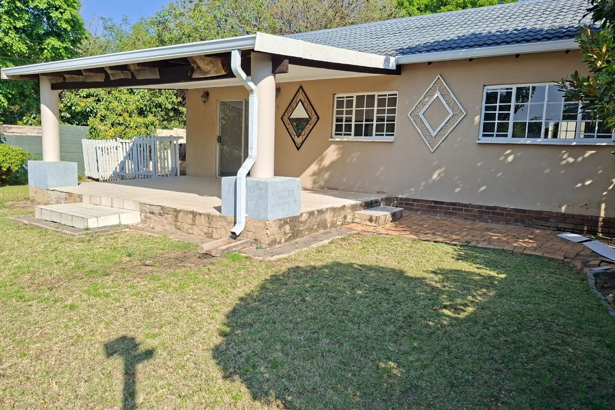 Rear view of the property featuring a covered patio area, tiled roof, and access to the garden through a sliding door.